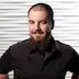 A professional headshot of Sebastian Inman, the founder of BetterA11y. He is a man with short hair, a beard, and a nose ring, smiling confidently with his hands on his hips. He wears a black button-down shirt against a textured white background.